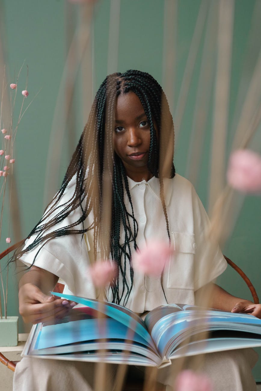 serious young black woman reading book in room with green walls